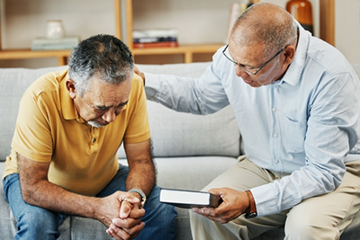 Grieving man receiving compassionate counseling while therapist offers faith-based support with a Bible