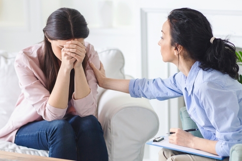 Compassionate Support During Grief Counseling Therapist comforting a crying female client during a grief counseling session